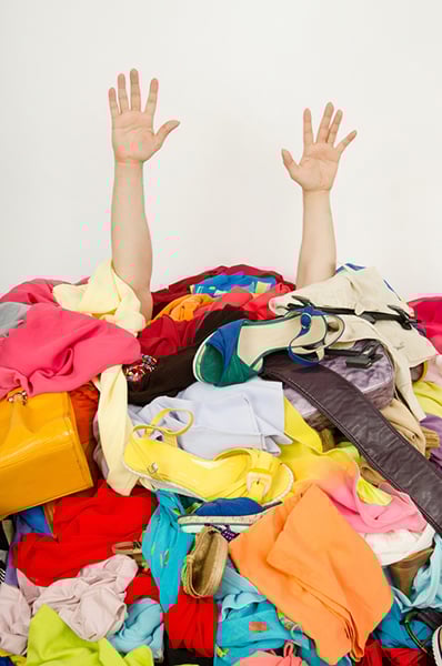 Underperforming keywords clutter PPC campaign strategy, remove them to save money and improve results. Two arms stick out from under a pile of clothes.