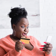 Design for user intent – transactional users are ones who are ready to take action. An excited woman looks at her phone while holding a credit card