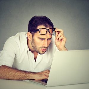 Avoid customer confusion with targeted microsites. A man leans towards his laptop computer, peering and lifting his spectacles.