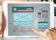 The Creative Momentum’s team has the skills to make your site look great. Someone touches a tablet devise displaying a wireframe picture.