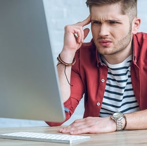 Poor web design workflow just leads to confusion. Man squints at a computer, while rubbing his temple.