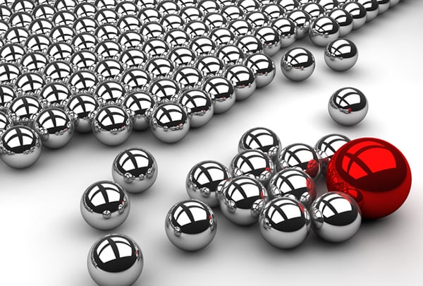 Influencers can affect how your target market thinks about you. Close-up, perspective view from the right side of silver magnetic balls. One larger red ball attracts the silver balls away from the group.
