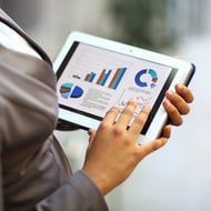 To ensure the greatest Google Ads pay per click ROI, you need to monitor the results - woman holding tablet displaying graphs